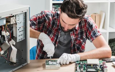 young-male-technician-wearing-gloves-fixing-computer-motherboard-with-screwdriver