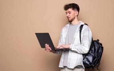 young-male-student-with-modern-laptop-color-background